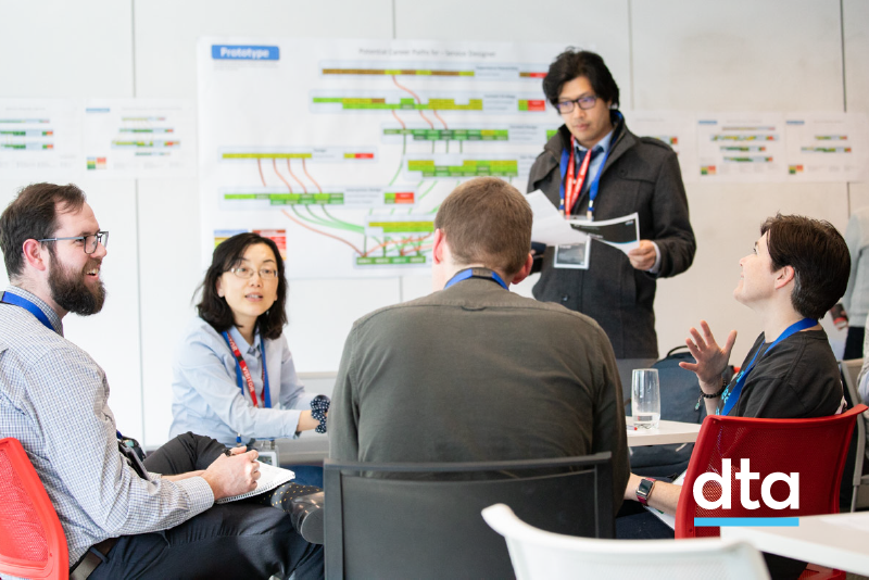 5 people sitting and standing in front of a diagram.