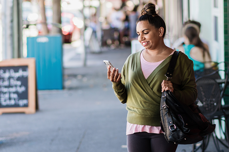 A person walking along the street looking at their phone.